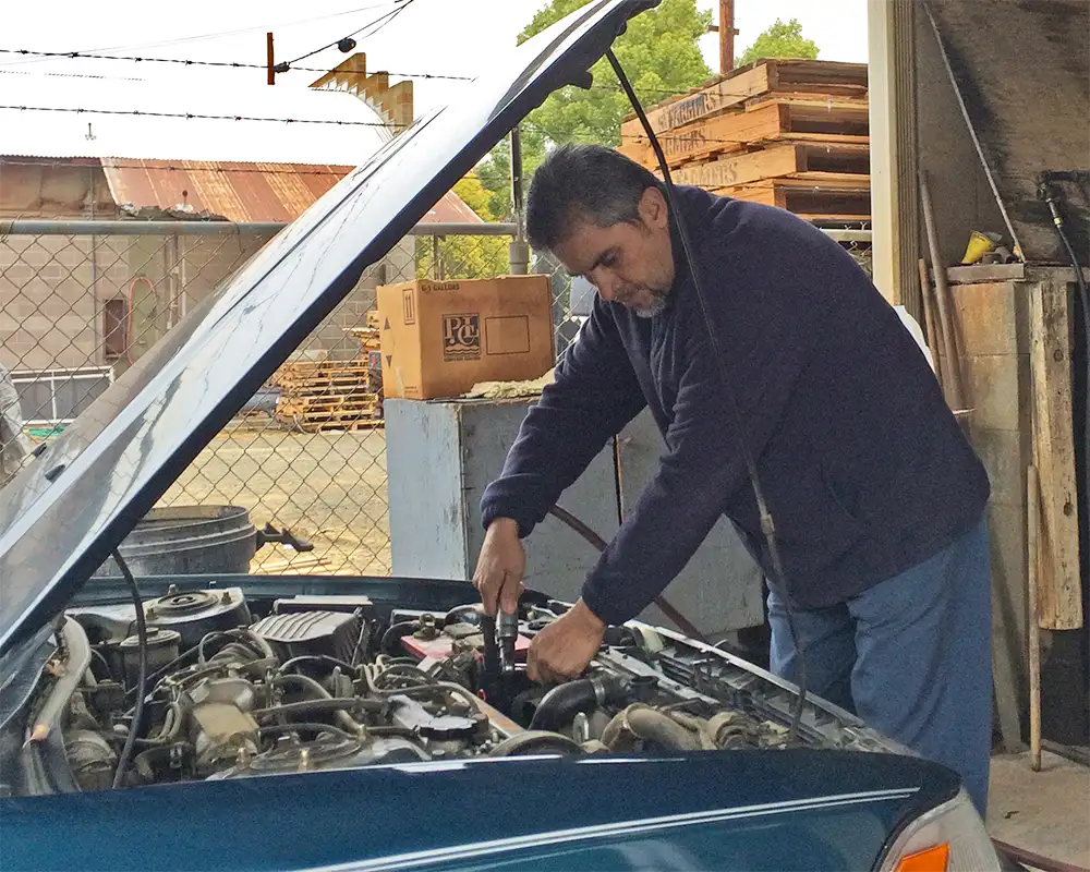 Radiator Shop repairman leading over a car engine